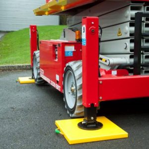 Outrigger leg on yellow hi-viz pad supporting a red mobile lift on tarmac near grass verge